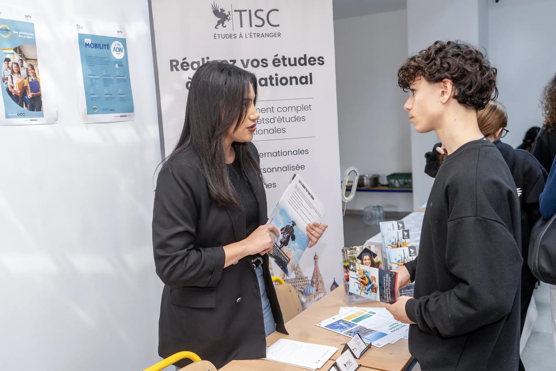 TISC advisor presenting a brochure to a student at a fair